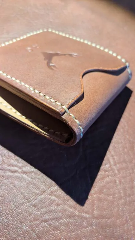 Close-up of hand-stitched leather wallet with rounded edge and contrast stitching